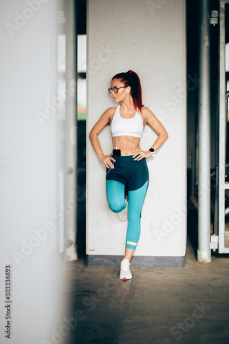 Attractive woman wearing sports clothing listening to music while stretching and working out