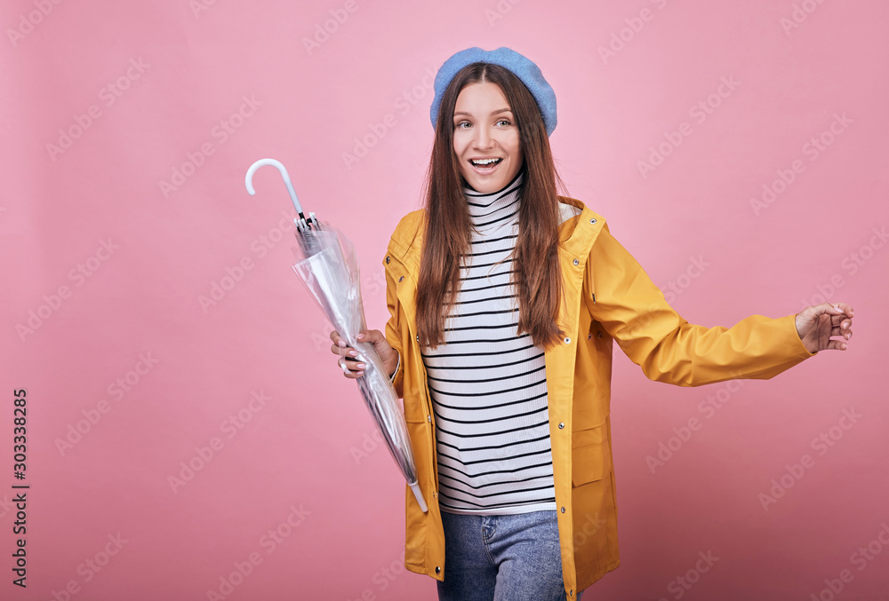 Cool cheerful girl in striped blouse and raincoat is runing with closed umbrella Cool cheerful girl in striped blouse and raincoat is runing with closed umbrella