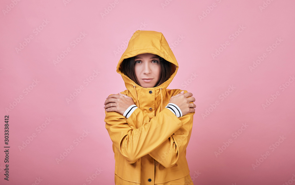 Fotografie Cool charming sad girl raincoat with dressed hood is frozen and trembling