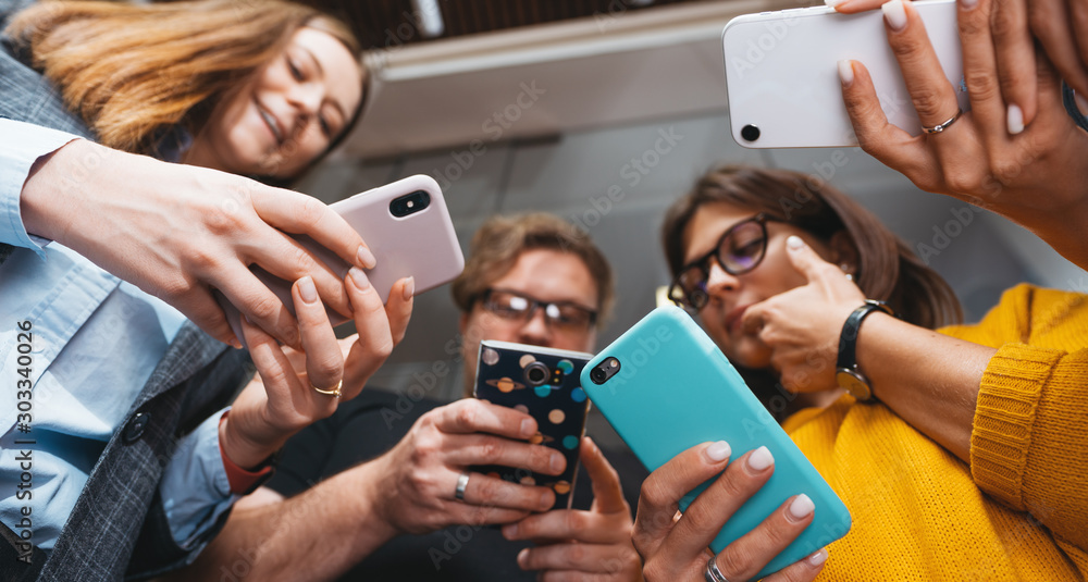 Group of business people stand in line hold smartphone. Wide shot. Positive office employees standing together and holding phone in hands - obrazy, fototapety, plakaty 