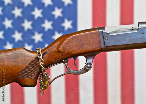 Lever action rifle with padlocked chain and American flag in background. photo