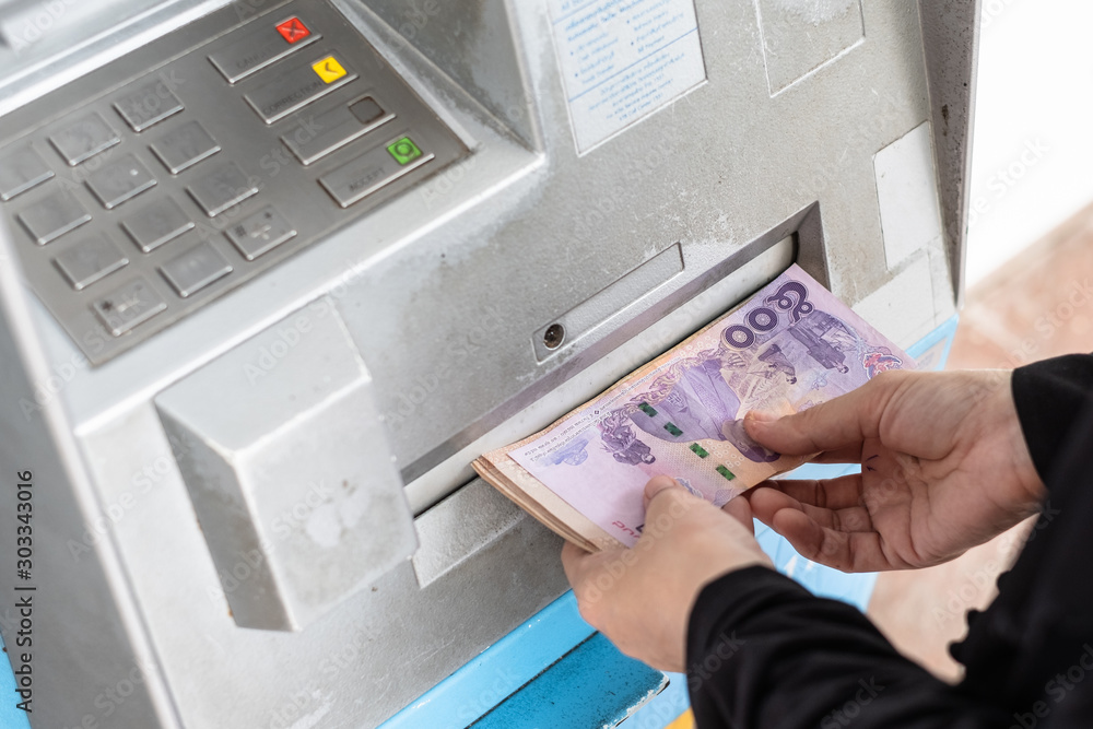 Close up of hand withdraw money in Thai baht currency from bank machine. Cash out money at an ATM. Close up of hand withdraw money in Thai baht currency from bank machine. Cash out money at an ATM.