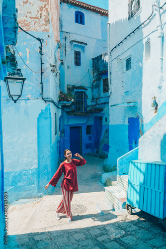 girl in asian clothes dancing on the street of the blue city of morocco