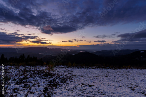 Sunset panorama in the Black Forest Mountains at golden hour with some fog and cloudy sky 