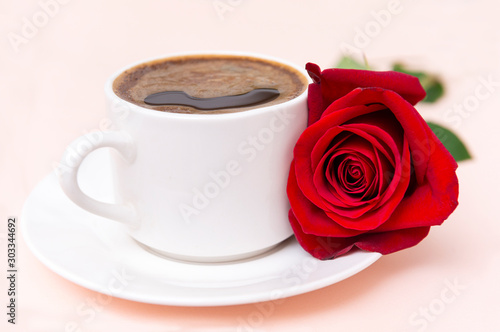Cup of black coffee with red rose flower on a beige background