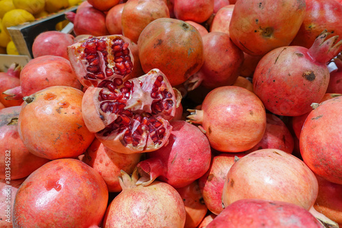 Broken pomegranate on a pile of red pomegranates in the market