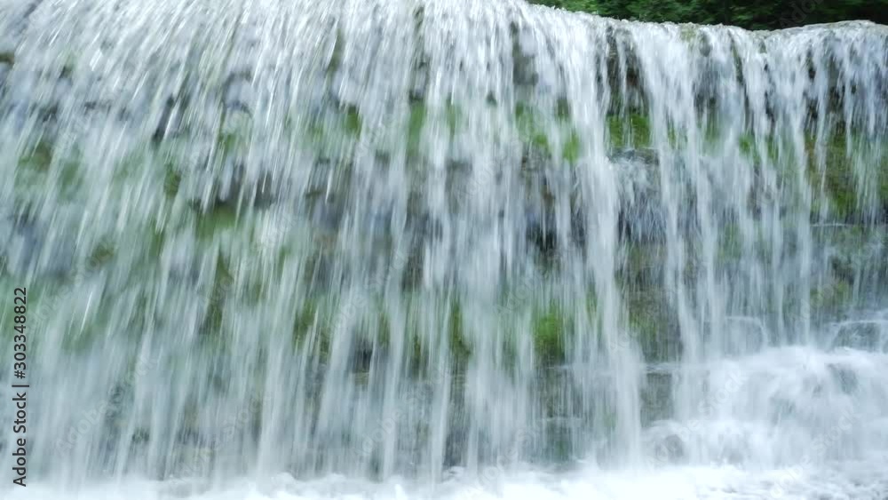 Panning across wide waterfall in the middle of a forest Panning across wide waterfall in the middle of a forest