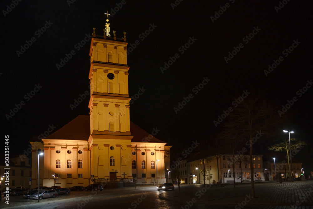 Neustrelitz city church illuminated at night on the market place, cityscape with copy space in the black sky, Mecklenburg-Vorpommern, Germany