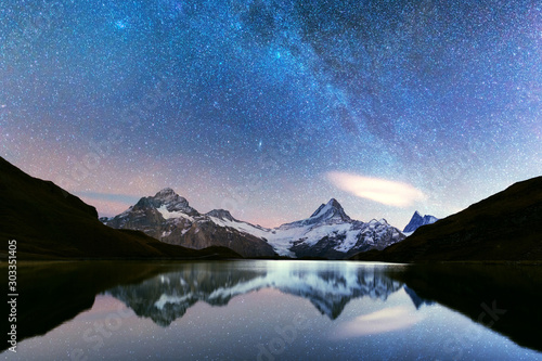Incredible night view of Bachalpsee lake in Swiss Alps mountains. Snowy peaks of Wetterhorn, Mittelhorn and Rosenhorn on background. Grindelwald valley, Switzerland. Landscape astrophotography photo