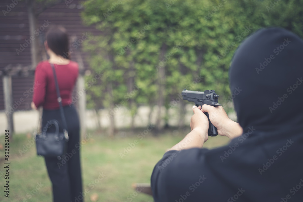 bandit using black gun point to backward of woman, concept of criminal, bandit, gangster, mafia bandit using black gun point to backward of woman, concept of criminal, bandit, gangster, mafia