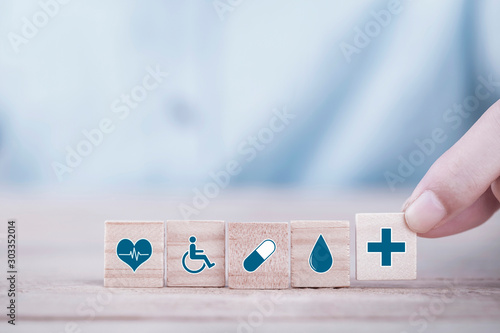 Hand chooses a emoticon icons healthcare medical symbol on wooden block , Healthcare and medical Insurance concept