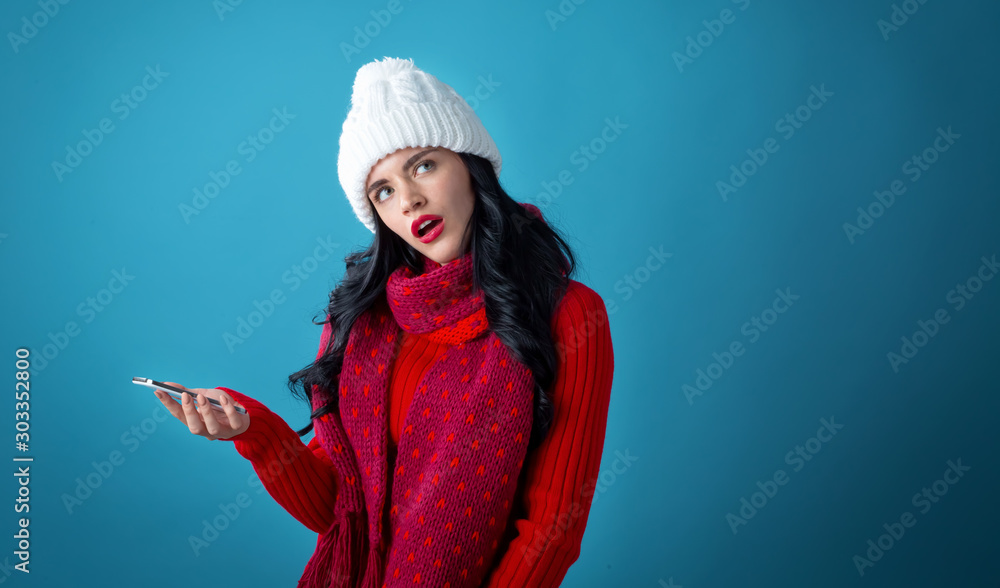 Young woman with Christmas theme using her phone on a dark blue background Young woman with Christmas theme using her phone on a dark blue background