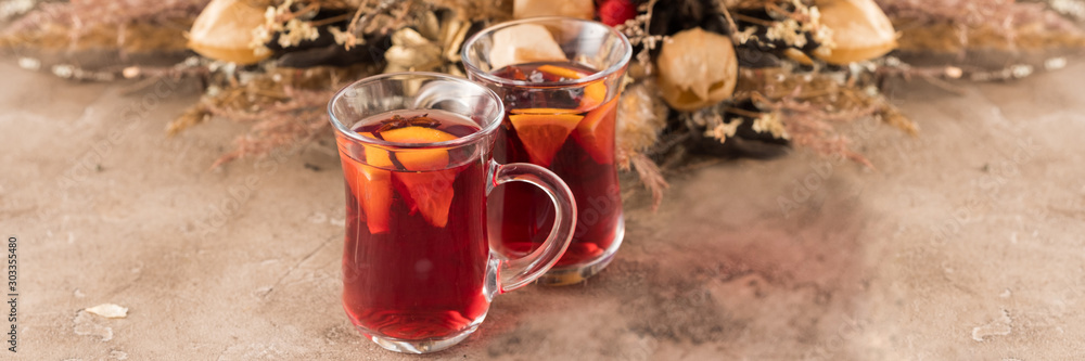 Two glasses of christmas mulled wine with oranges and spices on a textural background. Selective focus. Copy space. Banner. Two glasses of christmas mulled wine with oranges and spices on a textural background. Selective focus. Copy space. Banner.