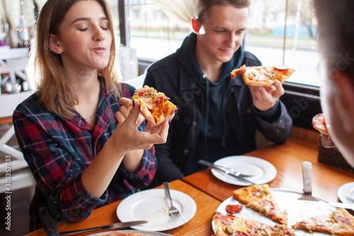 couple sits in a pizzeria and eats pizza, a guy and a girl dine fast food, smile and relax in a restaurant
