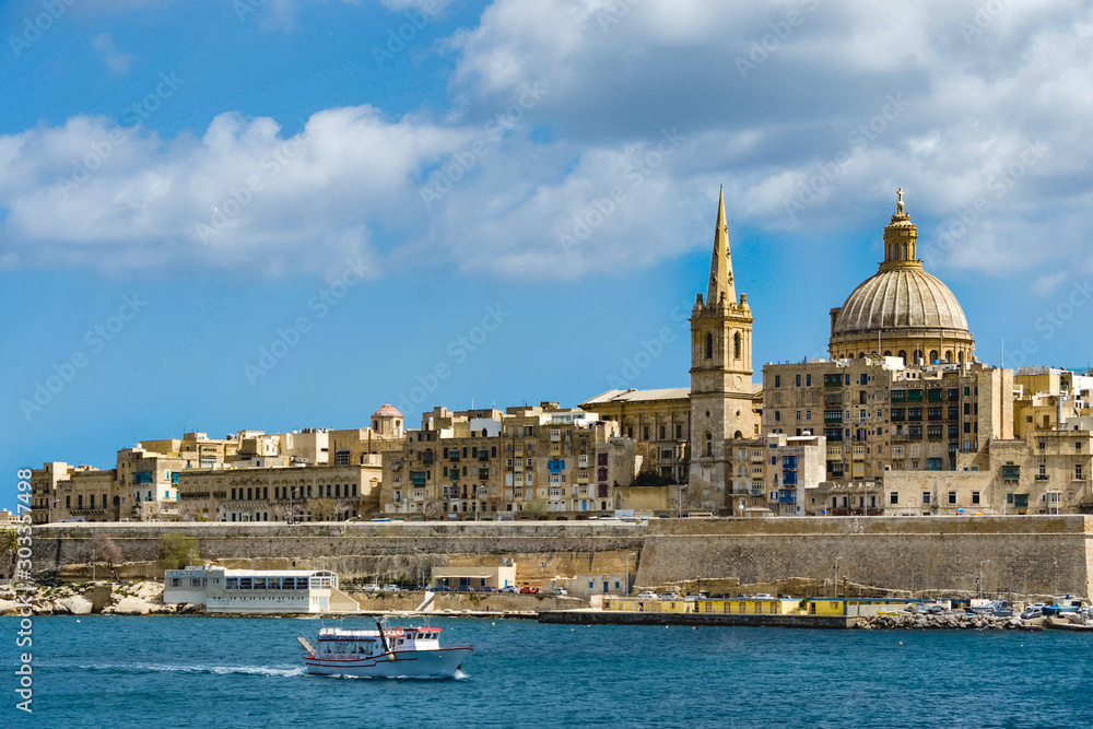 A boat on Marsamxett harbour sails pass the city of Valletta, Malta.