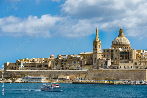 A boat on Marsamxett harbour sails pass the city of Valletta, Malta.