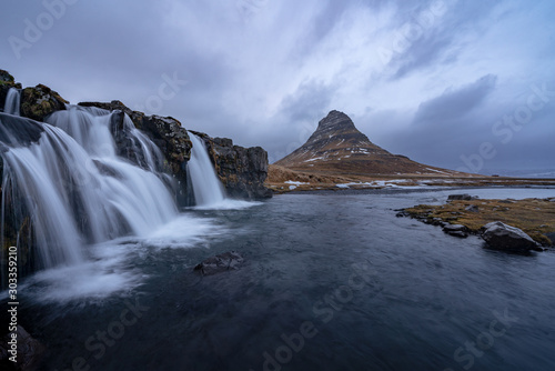 Famous mountain with waterfalls in Iceland, kirkjufell, winter in Iceland, ice and snow, reflections, yellow grass, nature, icelandic famous landscape