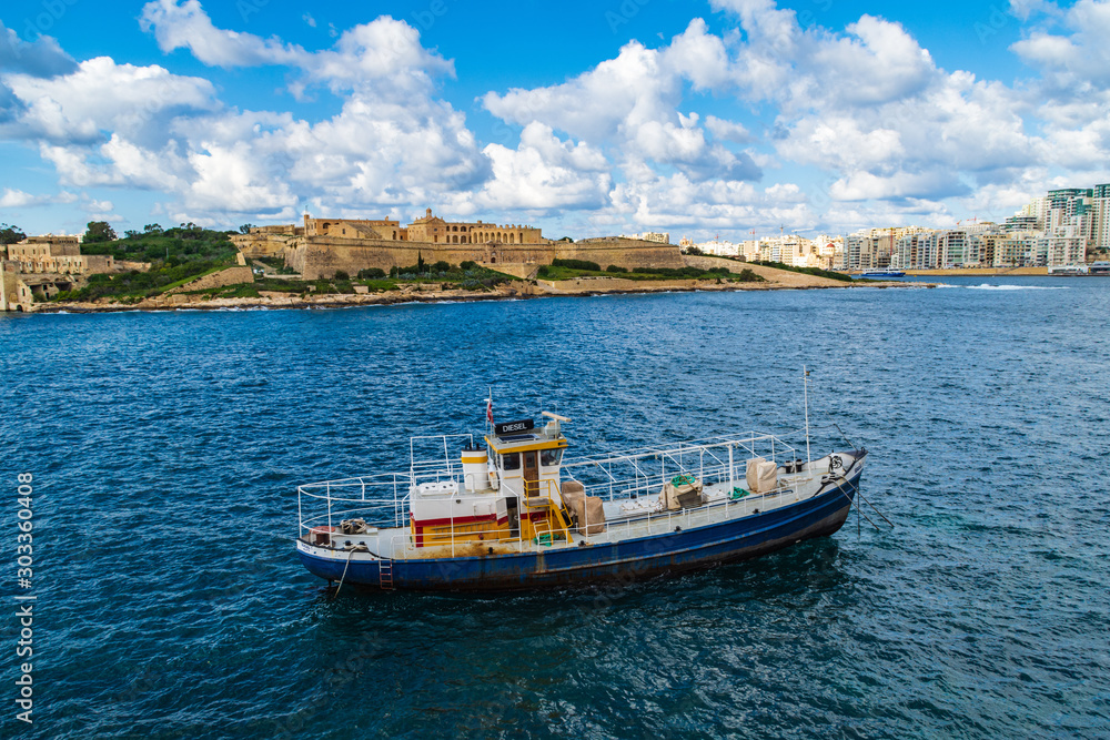 A boat mored in Marsamxett Harbour, in front of Fort Manoel, Malta
