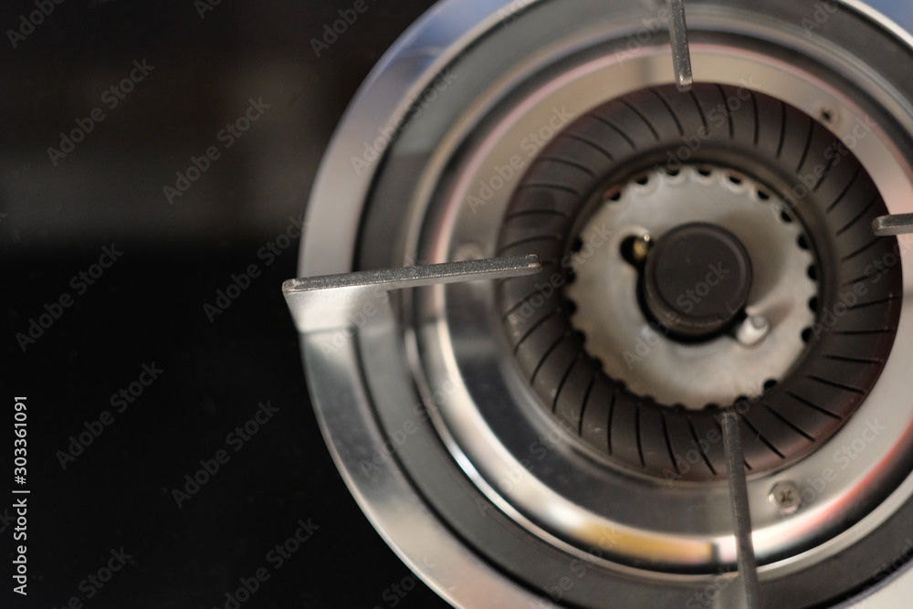 top view of part of shiny silver gas stove. black background