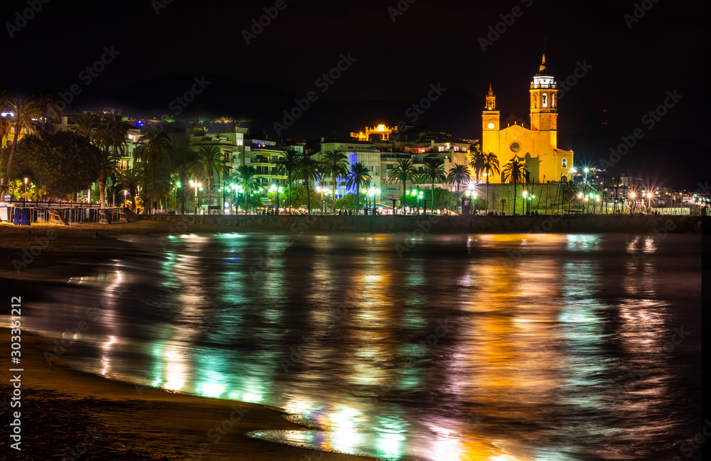 coastal town at night with lighting on the promenade and church in the background - image