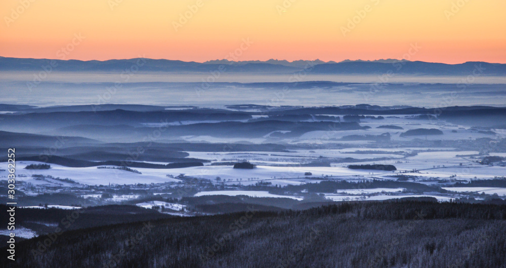 Sunrise in snow covered Jeseniky mountains in Czechia during nice winter with fog and clear sky. Wiew of Czech mountains, trees and snow fields covered in snow and morning sun. Eastern Sudetes, Praded