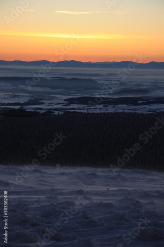 Sunrise in snow covered Jeseniky mountains in Czechia during nice winter with fog and clear sky. Wiew of Czech mountains, trees and snow fields covered in snow and morning sun. Eastern Sudetes, Praded