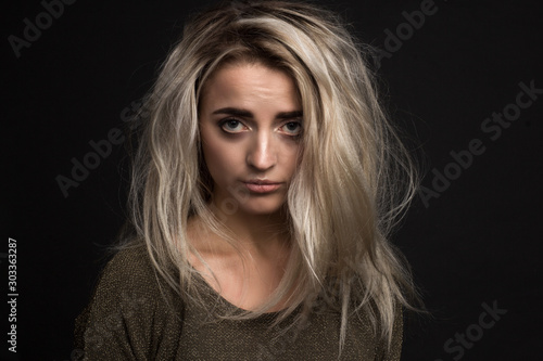 Obraz na płótnie portrait of a young beautiful girl with an offended expression and disheveled hair on a black background w salonie
