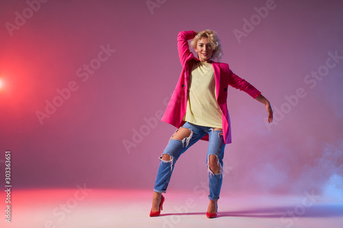 Smiling jazz dancer performing on dance stage, demonstrating dance element, spreading hand sideways, beauty fashion concept, trendy make up