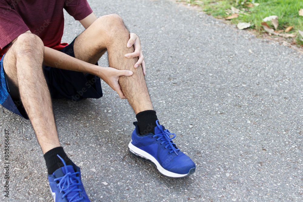 Close up of sport man suffering with pain on sports running knee injury after running.Injury from workout concept. Close up of sport man suffering with pain on sports running knee injury after running.Injury from workout concept.