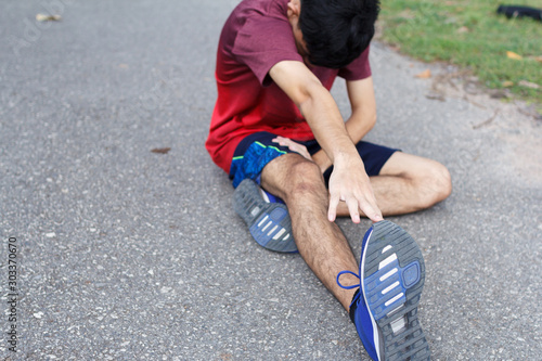 Young man runner stretching legs before run - workout concept