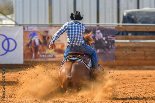The rear view of a rider stopping a horse in the sand. 