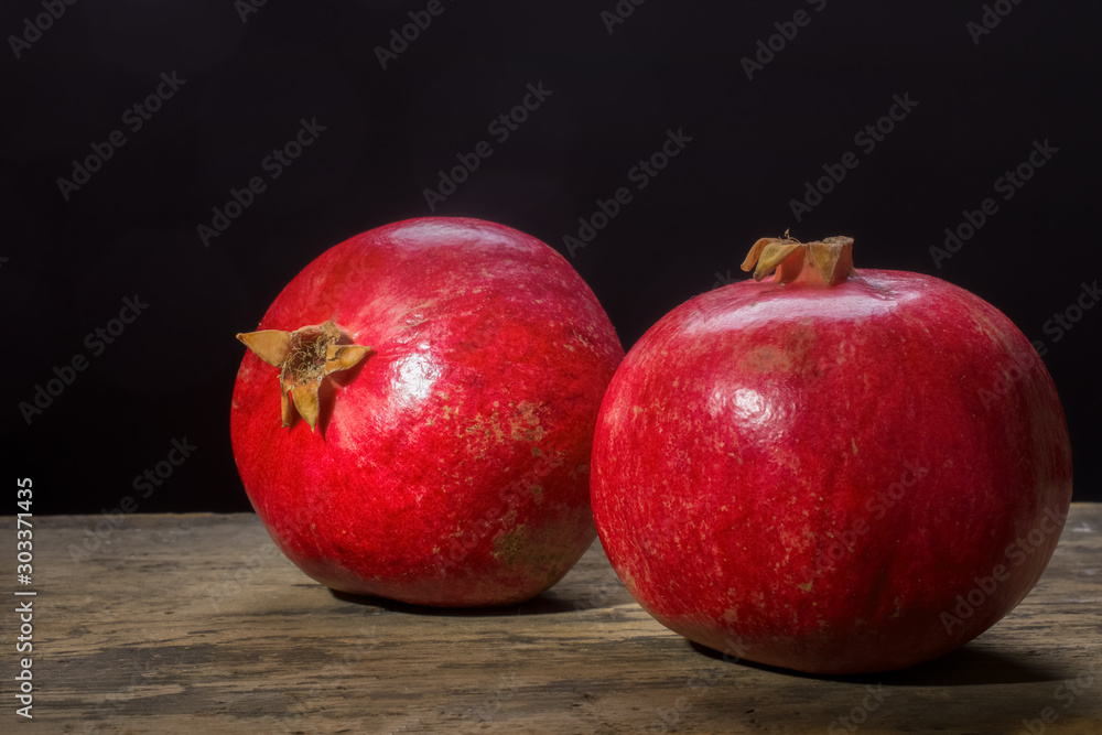 Ripe pomegranate on a wooden board on a dark background Ripe pomegranate on a wooden board on a dark background