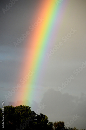 The end of the Rainbow, telephoto of a colorful rainbow in a foggy landscape.