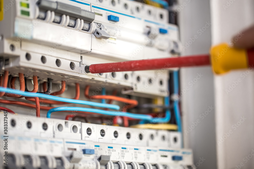 Man, an electrical technician working in a switchboard with fuses. Installation and connection of electrical equipment. Close up.