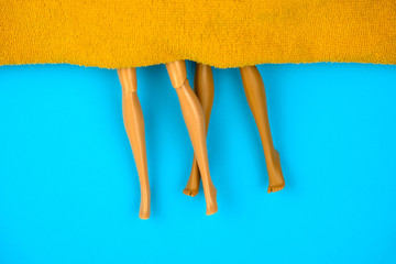 top view plastic dolls under orange blanket on a blue background,sex concept