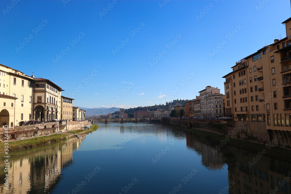 scenic view to Arno river from ponte vecchio in florence italy with bright blue sky