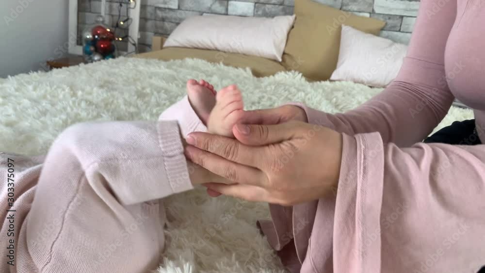 mother with tenderness holds the leg of her little daughter, doing a light foot massage, playing, healthy lifestyle, happy parents, childhood mother with tenderness holds the leg of her little daughter, doing a light foot massage, playing, healthy lifestyle, happy parents, childhood