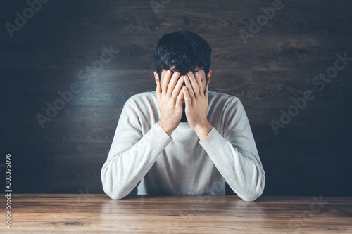.sad man hand on head on dark background