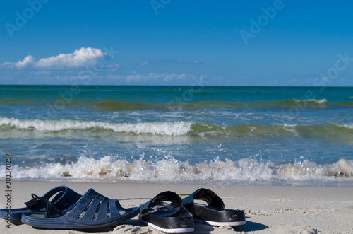 Slippers in front of the sea, vacation in two, slippers after entering the sea, romantic vacation by the ocean, love.