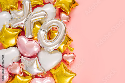 XO foil balloon letters and air balloons of heart shaped and stars. Love concept.  Valentine s Day or wedding bachelorette party decoration. Colorful Metallic air balloons on pink background.