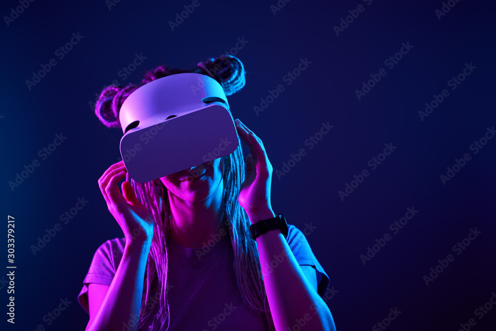 Woman is using virtual reality headset. Neon light studio portrait. Woman is using virtual reality headset. Neon light studio portrait.