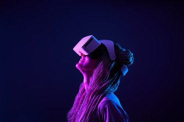 Woman is using virtual reality headset. Neon light studio portrait.