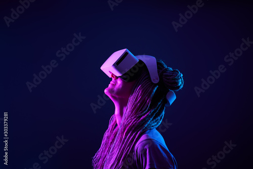 Woman is using virtual reality headset. Neon light studio portrait. photo