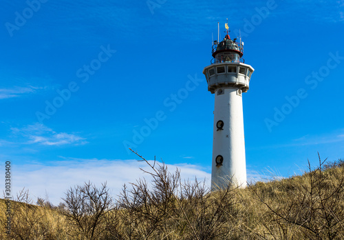 the white lighthouse of egmond aan zee, standing on a dune hill in northern holland. famous old landmark in the toruristic seaside of the netherlands.