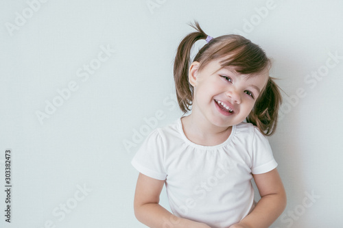 portrait of smiling baby girl with ponytails and in a white t-shirt