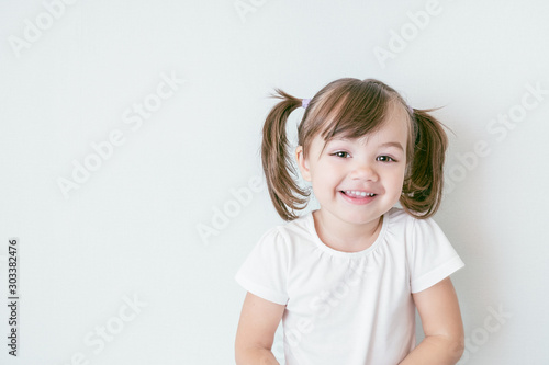 portrait of smiling baby girl with ponytails and in a white t-shirt