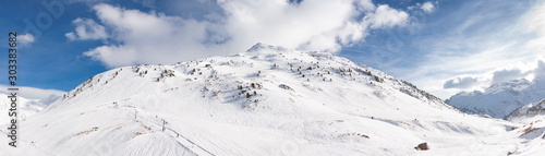 Vista panorámica de paisaje de montaña cubierto de nieve con cielo azul y nubes