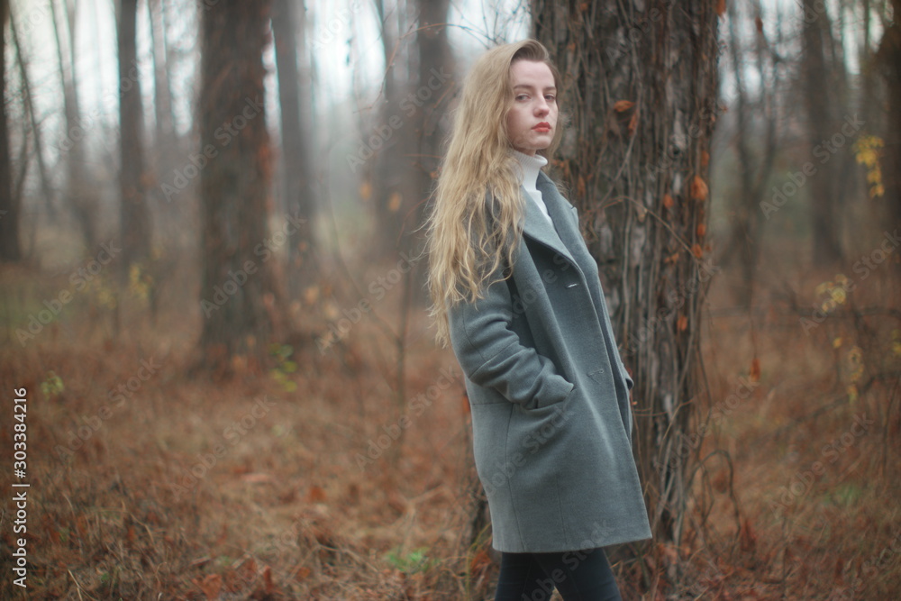 beautiful young blonde with long flowing hair on a blurry background of autumn coniferous forest beautiful young blonde with long flowing hair on a blurry background of autumn coniferous forest