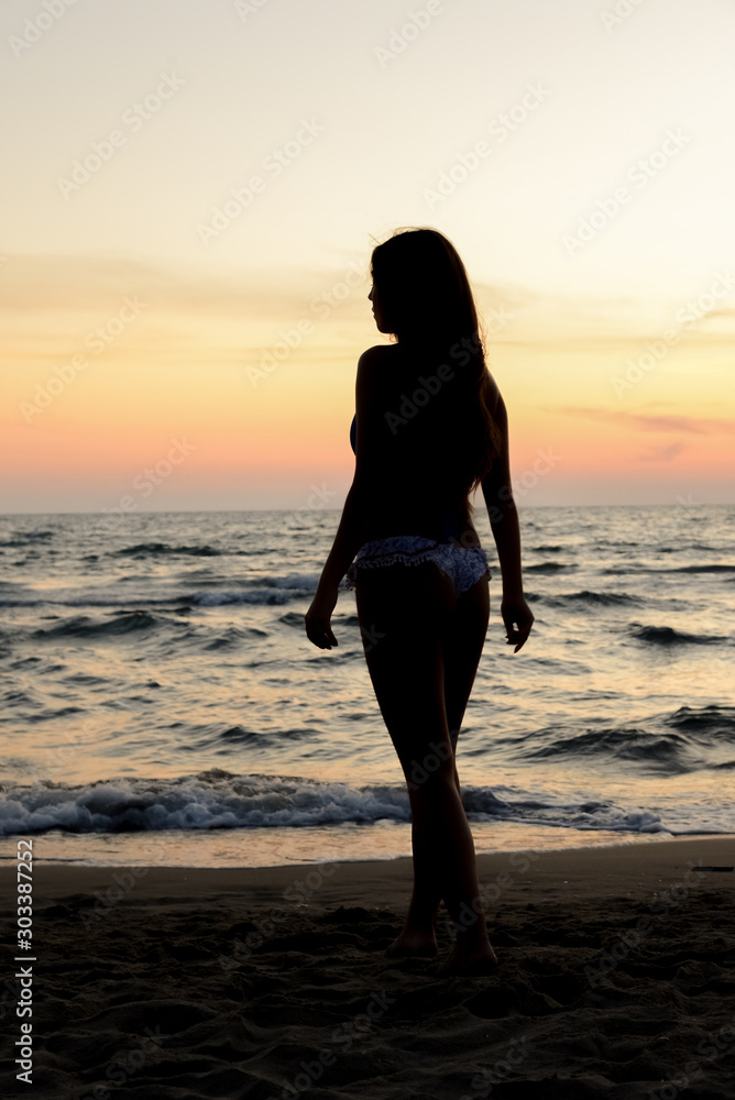 Young beautiful girl on the beach at sunset