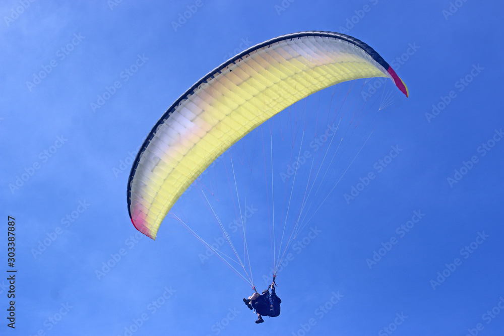 Tandem Paraglider flying wing in a blue sky Tandem Paraglider flying wing in a blue sky